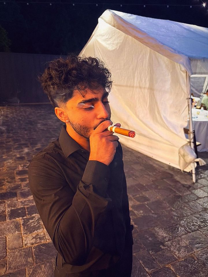YNGM0M0 (YNGMOMO) smoking a cigar outdoors at night in a black shirt