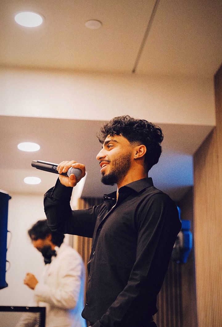 YNGM0M0 (Young Momo) performing live with a microphone, wearing a black button-up shirt